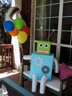 a toy robot sitting on top of a chair with balloons attached to it's back