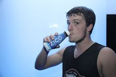 a young man is drinking from a bottle