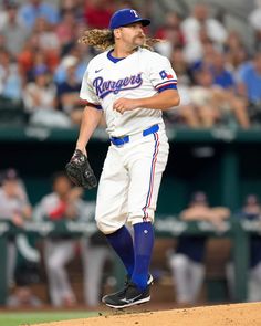 a baseball player in the process of throwing a ball during a game with fans watching