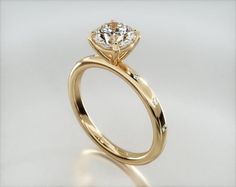 a yellow gold engagement ring with a round diamond