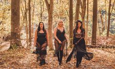 three women standing in the woods posing for a photo