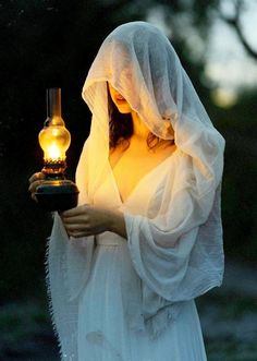 a woman dressed in white holding a light bulb