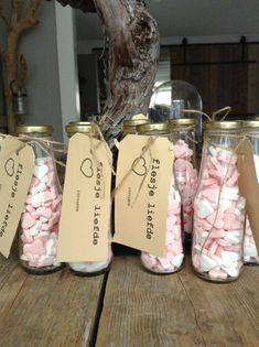 several jars filled with marshmallows sitting on top of a wooden table