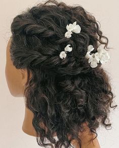 the back of a woman's head with white flowers in her hair and curls