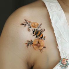 a woman's chest with flowers and a bee tattoo on her left side breast