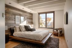 a large bed sitting under a window next to a wooden headboard and foot board