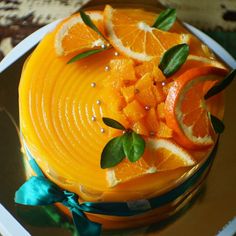 a cake with orange slices and green leaves on it's top, sitting on a plate