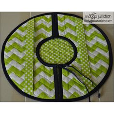 a green and white quilted table top with a sewing needle in the center on it