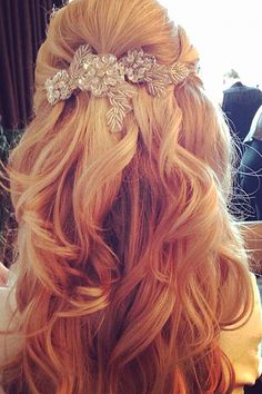 the back of a woman's head with long, wavy hair and flowers in her hair