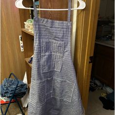 an apron hanging on a clothes rack next to a wooden closet with other items in it