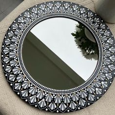 a round mirror sitting on top of a table next to a potted plant in a vase