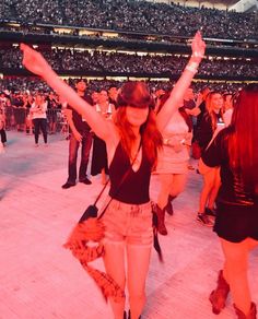 a woman with her arms in the air at a concert