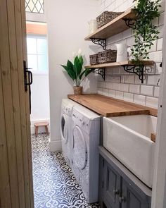 a washer and dryer in a small room with shelves on the wall above them