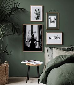 a bedroom with green walls and pictures hanging on the wall above the bed, along with a small side table