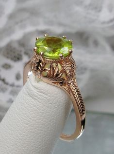 "Natural Peridot Ring Description Elizabeth Design#158 MADE TO ORDER Here we have a Victorian/Edwardian reproduction ring in sterling silver with rose gold overlay (rose gold \"embraced\") filigree with a natural peridot gemstone. This solitaire full cut round cut amethyst is 8mm in diameter. This ring also sits 8mm off the finger. The inside of the band is marked 925 for sterling. Notice the beautiful leaf design of the silver and gold filigree setting and etched band. This is a lovely renditio Oval Peridot Wedding Ring, Antique May Birthstone Rings For Wedding, Oval Peridot Jewelry For Wedding, Antique May Birthstone Wedding Rings, Round Peridot Wedding Rings, Peridot Ring For Wedding, Green Peridot Jewelry For Wedding, Art Deco Green Wedding Rings, Wedding Ring With Hallmarked Peridot