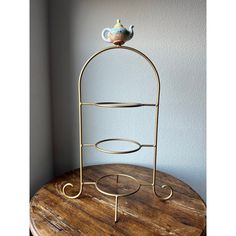 a metal rack with a teapot on top of it sitting on a wooden table