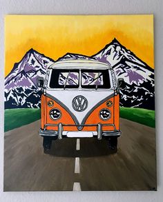 an orange and white vw bus driving down a road with mountains in the background