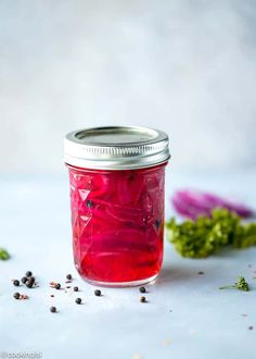 a jar filled with red liquid next to flowers