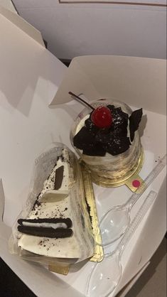 a piece of cake in a box with a cherry on top and some other items