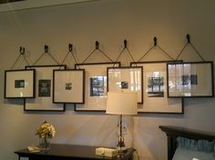 a wall with pictures hanging on it and a lamp in front of the photo frame