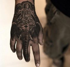 an elephant tattoo on the palm of a person's left hand, which is decorated with intricate designs