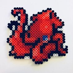 a red and black beaded brooch sitting on top of a white table next to a wall