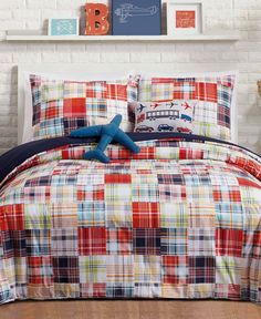 a bed with red, blue and white plaid comforter set on top of it