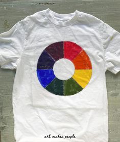 a white t - shirt with an image of a rainbow wheel on it's chest