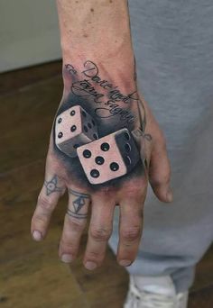 a man's hand with two dice tattoos on it