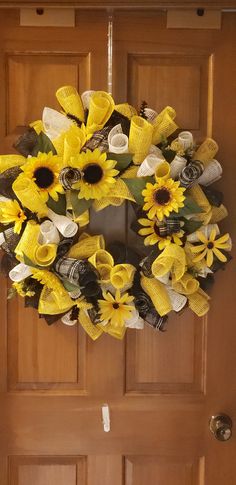 a sunflower wreath is hanging on the front door with ribbon and ribbons attached to it