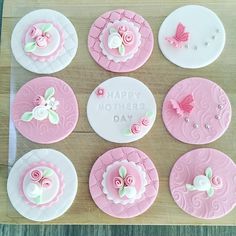 pink and white decorated cupcakes sitting on top of a cutting board with the words happy mothers day