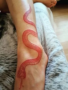 a woman's foot with a red snake tattoo on it