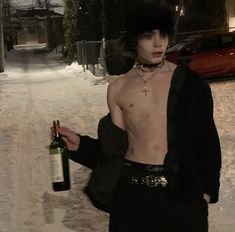 a shirtless man holding a bottle of wine in the middle of a snow covered street