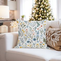 a living room with a christmas tree in the background and pillows on the couches