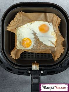 two fried eggs in a basket with brown paper