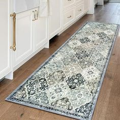 a large rug in the middle of a kitchen with white cabinets and counter tops on both sides