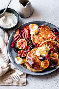 pancakes with fruit and yogurt are on a plate next to a cup of coffee