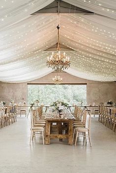 the inside of a tent with tables, chairs and chandeliers on it's ceiling