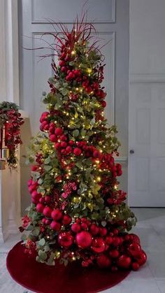 a christmas tree with red balls and greenery on the top is lit up by lights