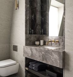 a bathroom with a toilet, sink and mirror in it's center wall next to a window