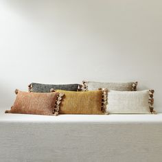 four decorative pillows on a white bed