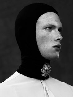 a woman wearing a black head covering with a flower brooch on her neck and face