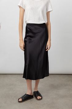 DETAILS | Super smooth, satin crepe, high-rise, unlined, sleek black midi skirt featuring black exposed elastic waistband, swingy fit, and flattering bias cut. Made with luxurious fabric in an easy pullover silhouette, this swingy skirt is perfect for work or play. 55% Rayon | 45% Viscose. Imported. CARE | Dry Clean Only. FIT | Recommend ordering true to size. Skirt Length: 31 1/2" (Measured from Small) Model is wearing size S.Model’s Measurements: Height 5’10“, Bust 32", Waist 24", Hips 34" Black Satin Midi Skirt, Crepe Skirts, Elegant Drapes, Satin Midi Skirt, Chunky Sandals, Slip Skirt, Minimal Chic, Black Midi Skirt, Black Midi