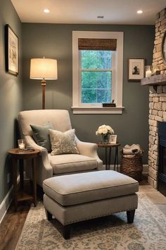 a living room with a chair, ottoman and window in the corner next to a fireplace