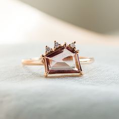 a pink and white diamond ring sitting on top of a bed with a white blanket