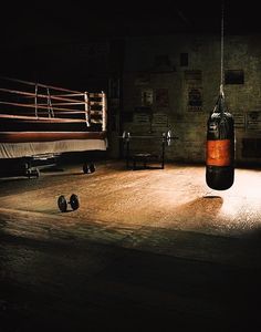 a boxing ring with two punching gloves hanging from the ceiling and other equipment on the floor