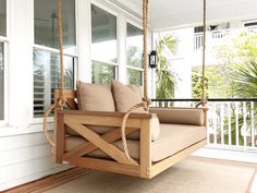 a wooden porch swing hanging from the side of a house