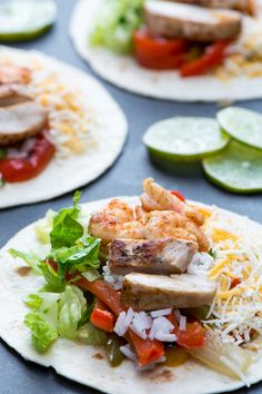 some tacos with shrimp, lettuce and tomatoes on them