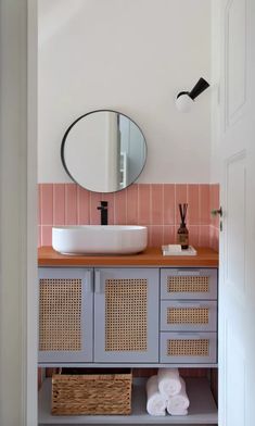 a bathroom with pink and white tiles on the wall, sink and mirror above it