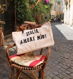 a white bag sitting on top of a wooden chair next to a tree and potted plant